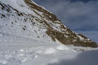 the shadow of a person standing on a snow covered slope near a mountain peak, in the background are a deep pile of snow