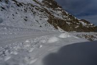 the shadow of a person standing on a snow covered slope near a mountain peak, in the background are a deep pile of snow