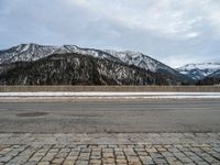 a snow - covered mountain range is seen on the edge of a highway with snow capped hills