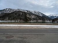 a snow - covered mountain range is seen on the edge of a highway with snow capped hills