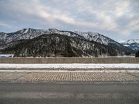 a snow - covered mountain range is seen on the edge of a highway with snow capped hills