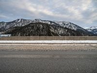 a snow - covered mountain range is seen on the edge of a highway with snow capped hills