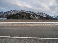 a snow - covered mountain range is seen on the edge of a highway with snow capped hills