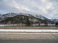 a snow - covered mountain range is seen on the edge of a highway with snow capped hills