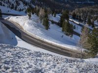 the side of a mountain road is snow covered with snow and trees are in the background