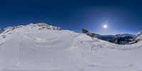 a snow covered hill with many tracks on it in the sun day and the full moon shining