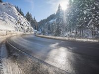 a mountain road with no vehicles or traffic is covered in snow and ice with pine trees in the background