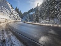 a mountain road with no vehicles or traffic is covered in snow and ice with pine trees in the background