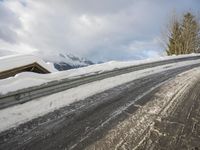 the road is completely covered with snow in the mountains near the lodge on a cold and cloudy day
