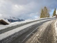 the road is completely covered with snow in the mountains near the lodge on a cold and cloudy day