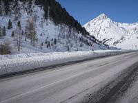 a snow covered mountain road going through it's center, with a clear sky