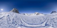 a very wide view of the snow in front of the mountains, with tracks drawn out on snow