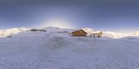 a small cabin in the middle of the snow covered mountains with a snow plow and mountains behind it