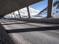 a view from under a bridge showing cars driving underneath the bridge in the snow covered mountains