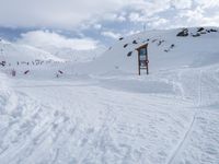 a ski lift going down the side of a mountain covered in snow and people on snowboards