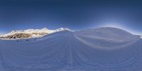 a man riding skis on top of snow covered ground under a blue sky over snow covered mountains