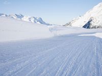 person on skis moving along the snowy road on a mountain side, looking back to the camera