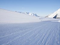 person on skis moving along the snowy road on a mountain side, looking back to the camera