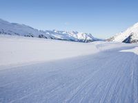 person on skis moving along the snowy road on a mountain side, looking back to the camera