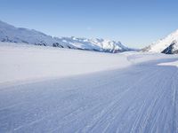 person on skis moving along the snowy road on a mountain side, looking back to the camera