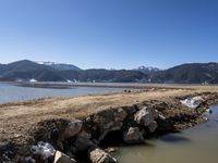 mountains with snow covered rocks sitting in the water next to a shore line and some water