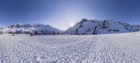 the sun shines over snow covered mountains with tent in front of them as viewed from below