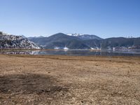 a dry field with many wind generators in the background and snow covered mountains on either side