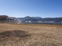 a dry field with many wind generators in the background and snow covered mountains on either side