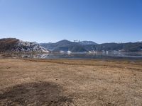 a dry field with many wind generators in the background and snow covered mountains on either side