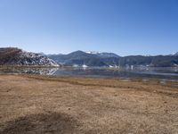 a dry field with many wind generators in the background and snow covered mountains on either side