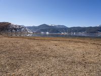 a dry field with many wind generators in the background and snow covered mountains on either side