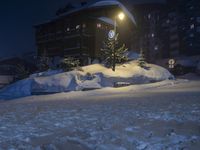 a street in front of a building lit up by the street light on a snow covered night