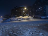 a street in front of a building lit up by the street light on a snow covered night