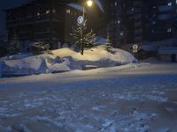 a street in front of a building lit up by the street light on a snow covered night