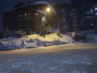 a street in front of a building lit up by the street light on a snow covered night