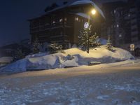 a street in front of a building lit up by the street light on a snow covered night