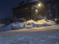 a street in front of a building lit up by the street light on a snow covered night