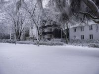 a person is walking through the snow covered park in front of a building with a white porch