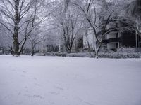 a person is walking through the snow covered park in front of a building with a white porch