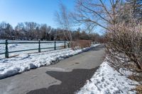 there is a snow covered area on the street in front of this park area with a path lined with snow