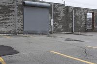 the empty parking lot has only snow on the ground in front of an old brick factory