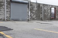 the empty parking lot has only snow on the ground in front of an old brick factory