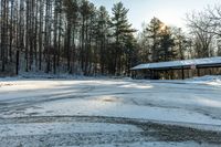 a small parking lot covered in snow and trees beside a building with an awning