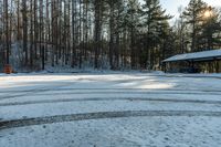 a small parking lot covered in snow and trees beside a building with an awning