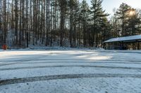 a small parking lot covered in snow and trees beside a building with an awning