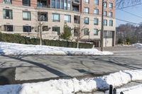 the parking meter on the sidewalk in front of some buildings with snow on it and a fence