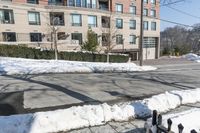 the parking meter on the sidewalk in front of some buildings with snow on it and a fence