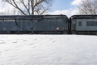 an old style train is on the tracks in snow next to some trees and blue skies