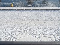 a fire hydrant near the edge of a river covered in snow next to a dock