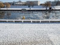 a fire hydrant near the edge of a river covered in snow next to a dock